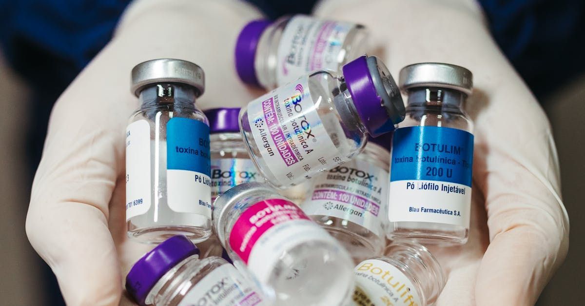 A person is holding a pile of bottles of vaccine in their hands.