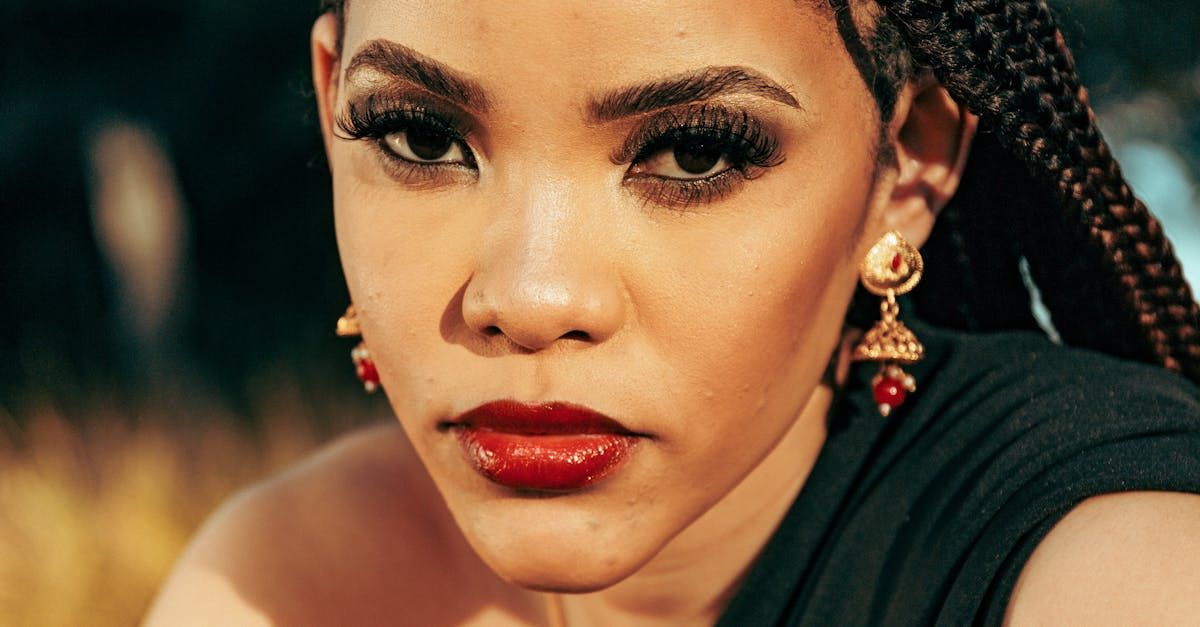 A close up of a woman wearing earrings and red lipstick.