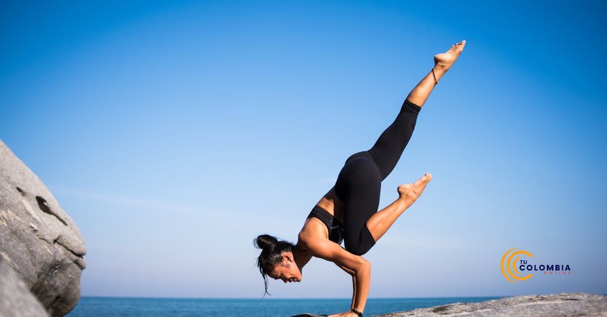 A woman is doing a handstand on a rock near the ocean.