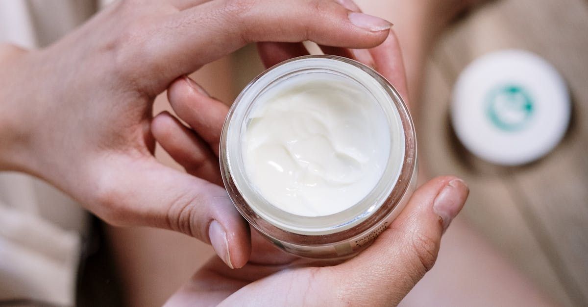 A person is holding a jar of cream in their hands.