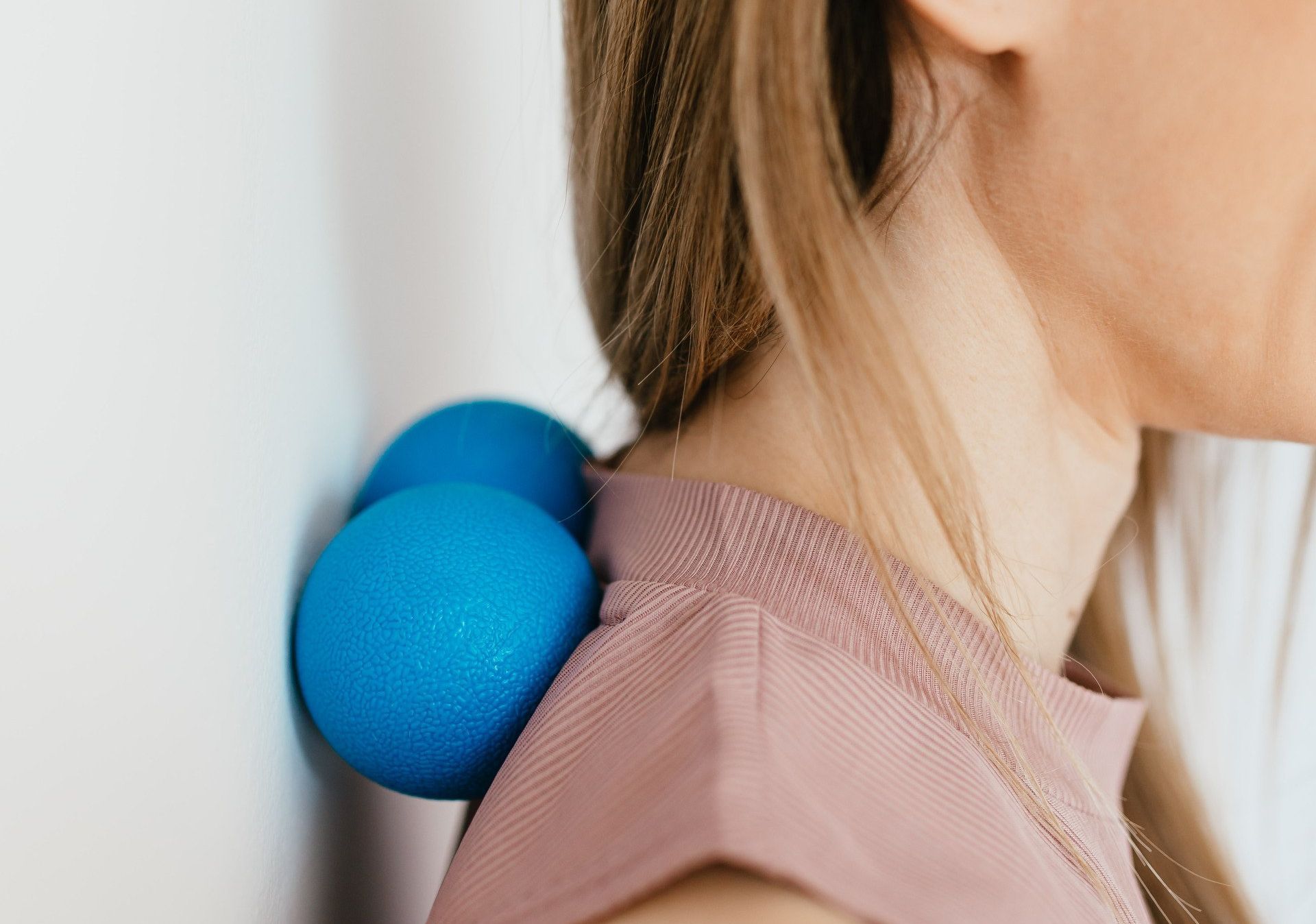 a woman is using a blue massage ball to massage her neck .