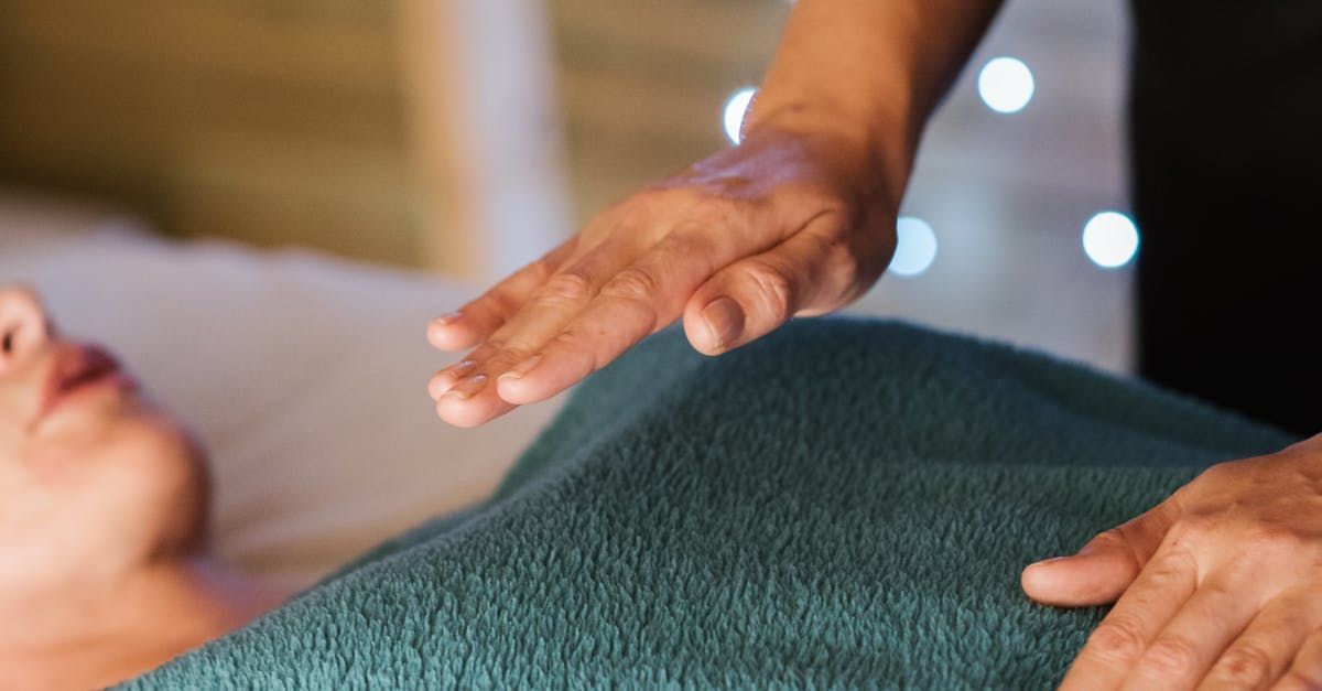 A woman is laying on a bed getting heat pad therapy.