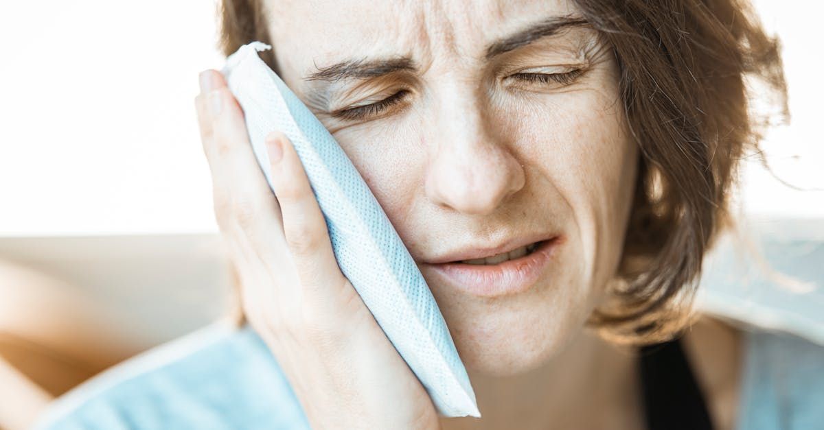 A woman is holding an ice pack to her face.