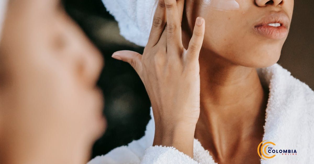 A woman is applying lotion to her face in front of a mirror.