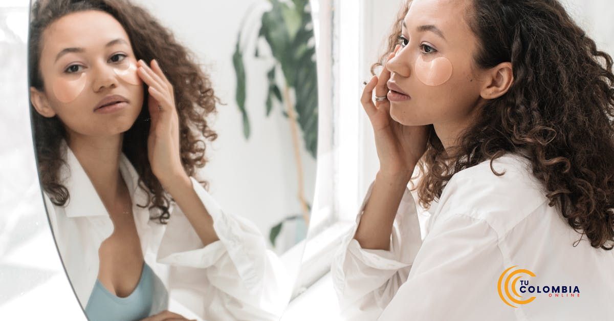 A woman is looking at her face in a mirror.