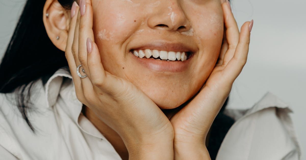 A woman is smiling with her hands on her face.