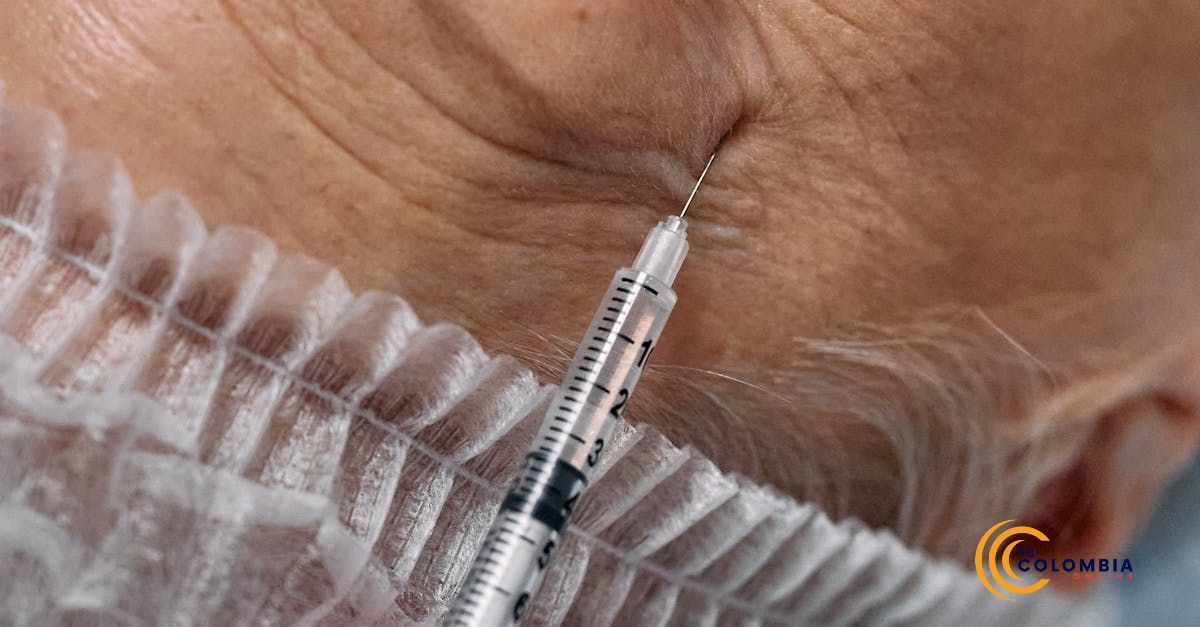 An older woman is getting a botox injection in her eye brow.