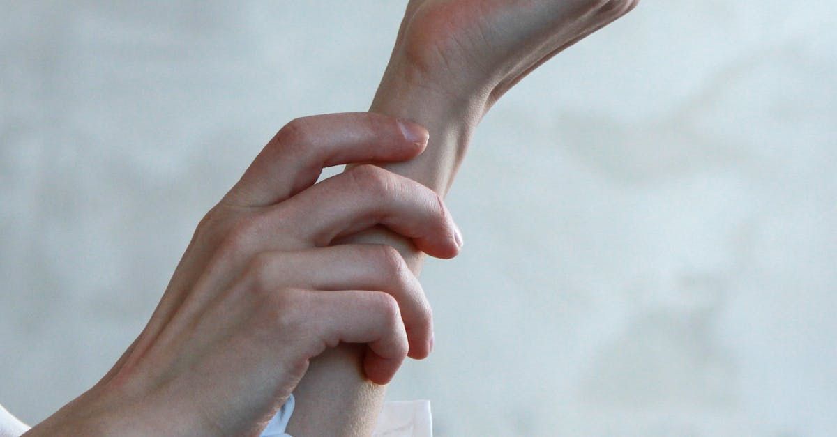 A close up of a person 's hands holding another person 's wrist.