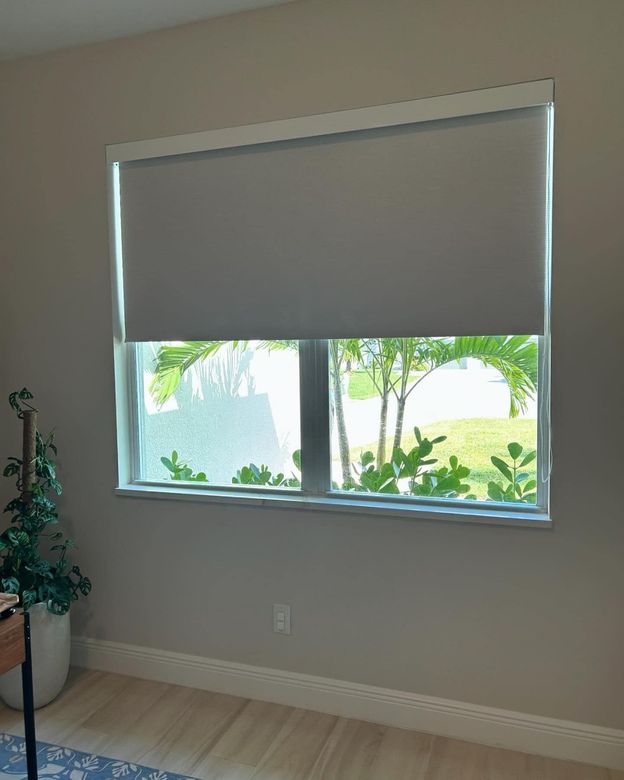 A living room with a large window with blinds on it.