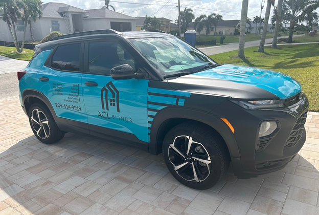 A blue and black suv is parked in front of a house.