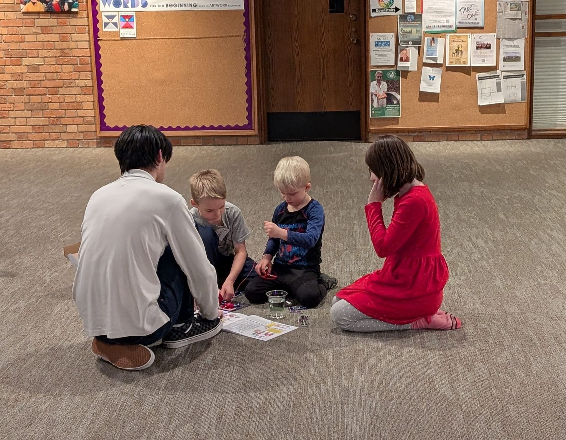 A group of people are sitting on the floor playing with toys.