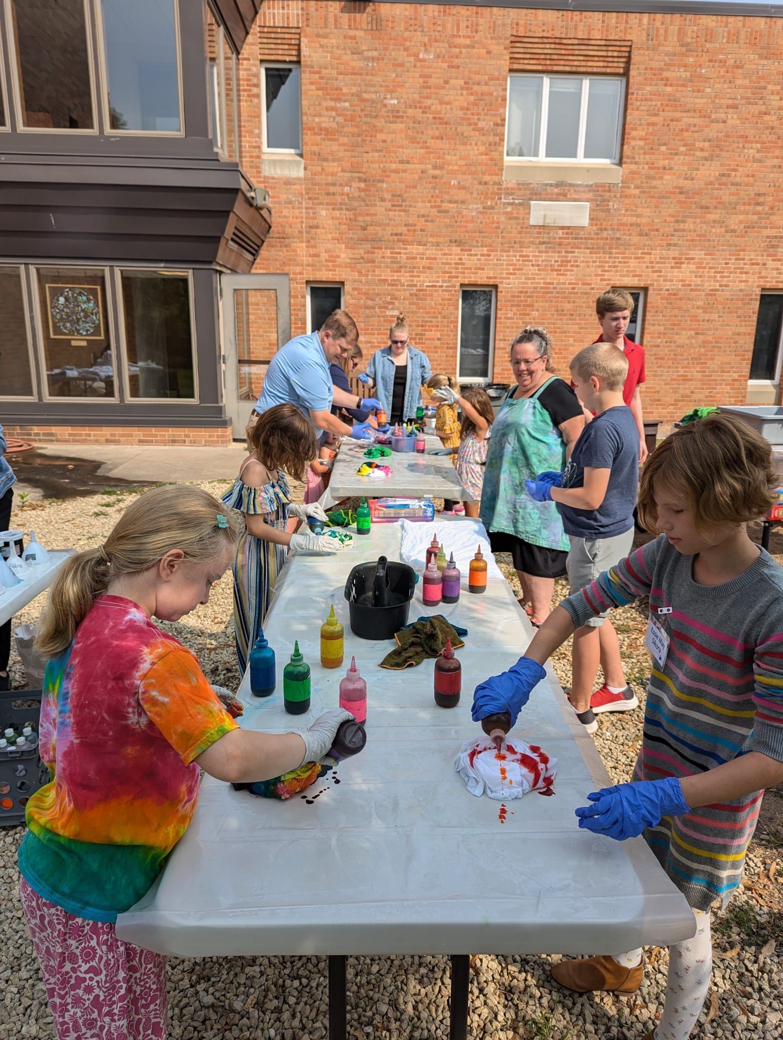 A group of children are sitting at a table with bottles of paint.
