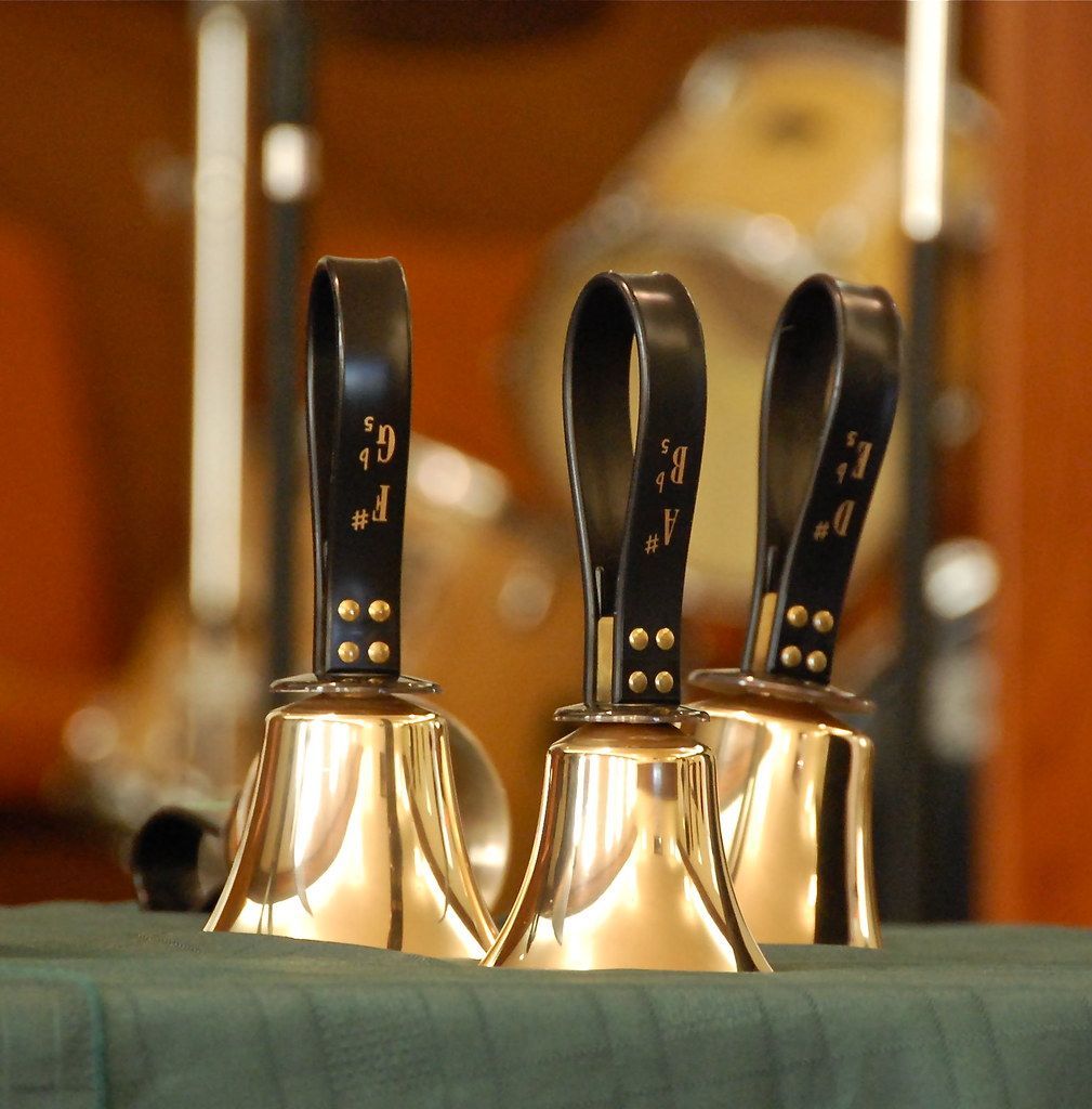 Three handbells are lined up on a table