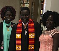 A man in a robe and scarf is standing next to two women.