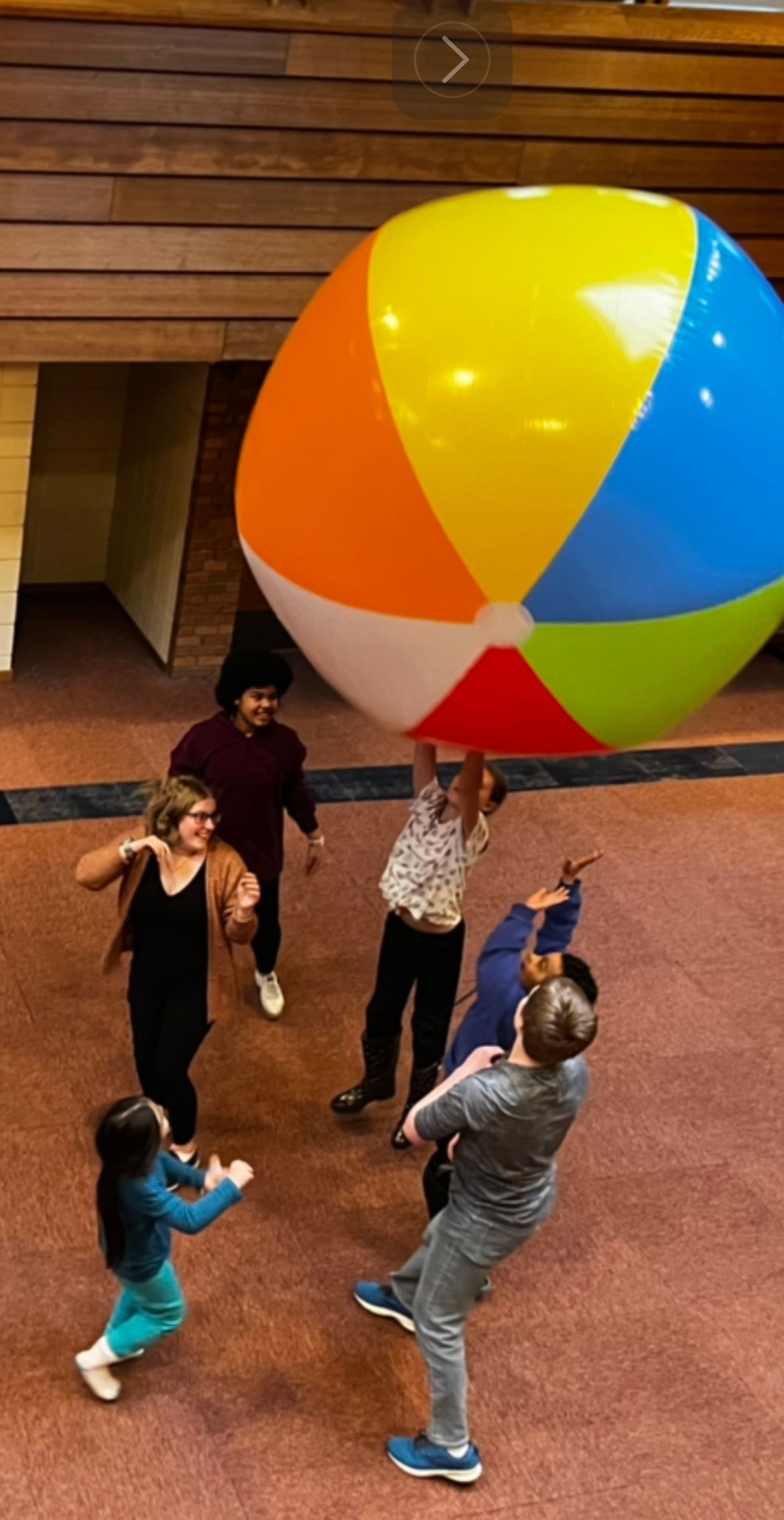 A group of young people are playing with a large beach ball