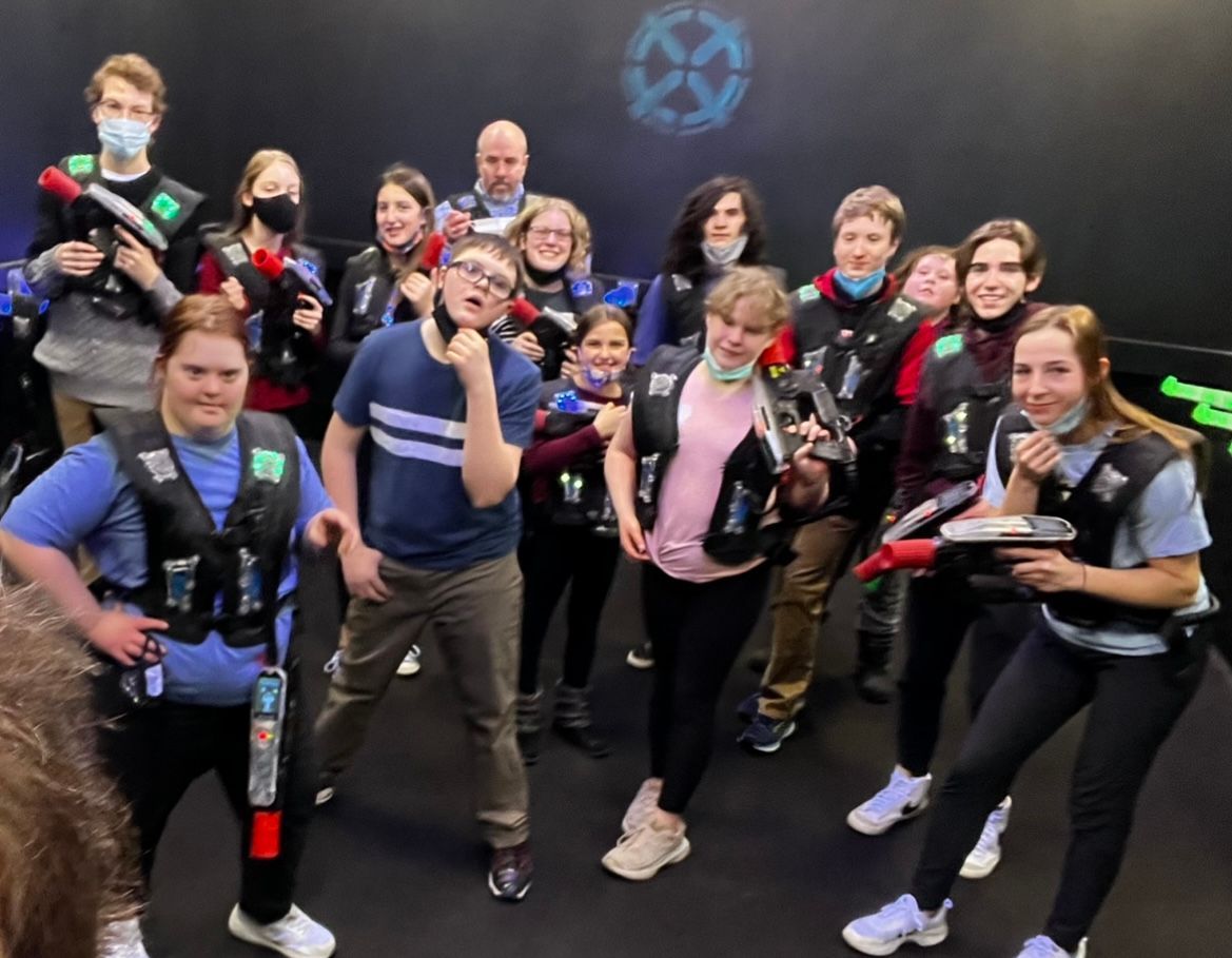 A group of young people are posing for a picture while playing laser tag.