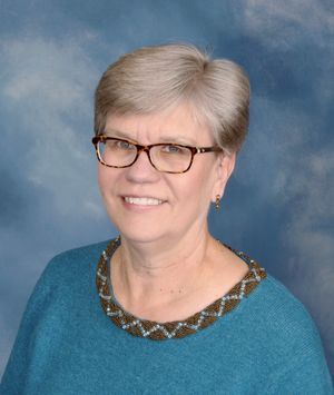 A woman wearing glasses is smiling for the camera.