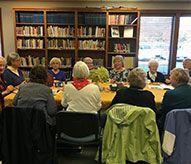 A group of people are sitting around a table in a library.