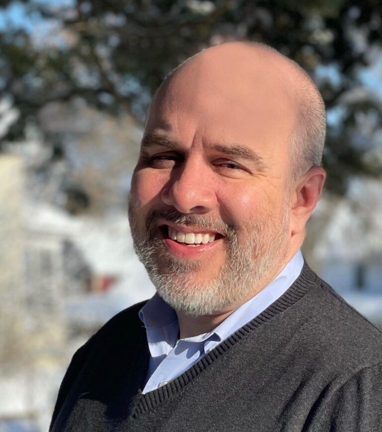 A man with a beard is smiling for the camera.