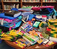 A table filled with lots of school supplies in a library.