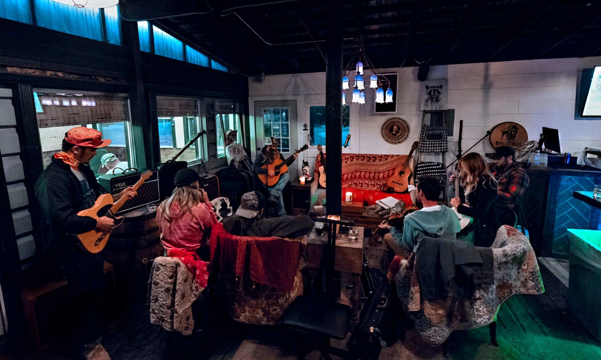 A group of people are sitting in a room playing guitars.
