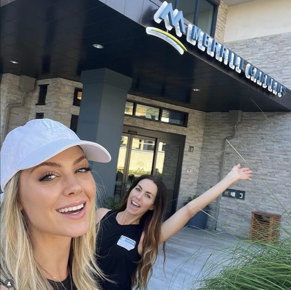 Two women smile near a building with 