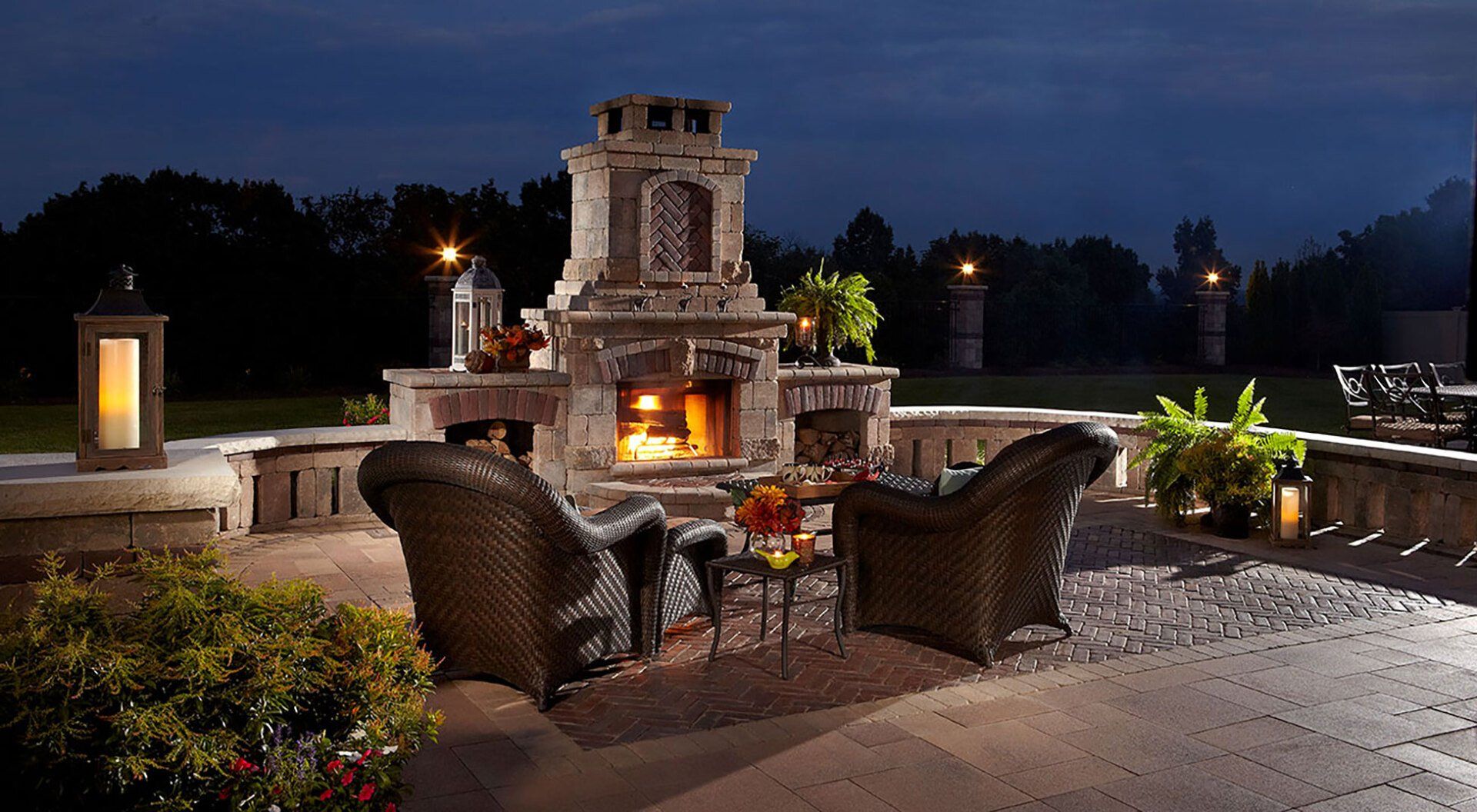 Outdoor living paver patio with pre built Unilock fireplace with wood boxes and poly outdoor furniture