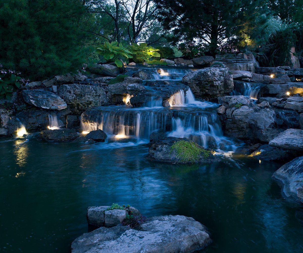 Waterfall cascade and landscape boulder lighting in Madison Ohio backyard pond