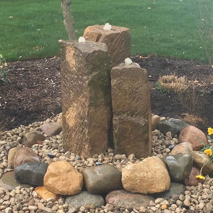 Natural barnstone bubbler water feature in Ohio backyard.