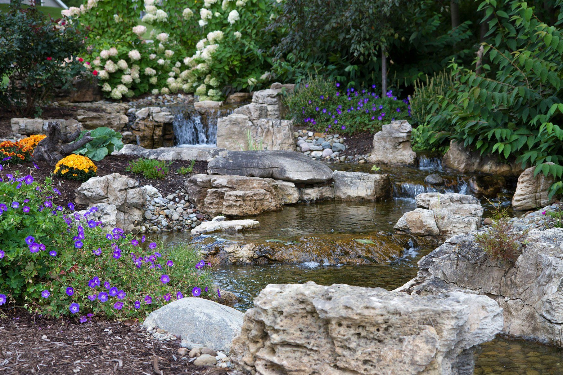 Ohio backyard patio long stream with pondless waterfall and large rocks and boulders