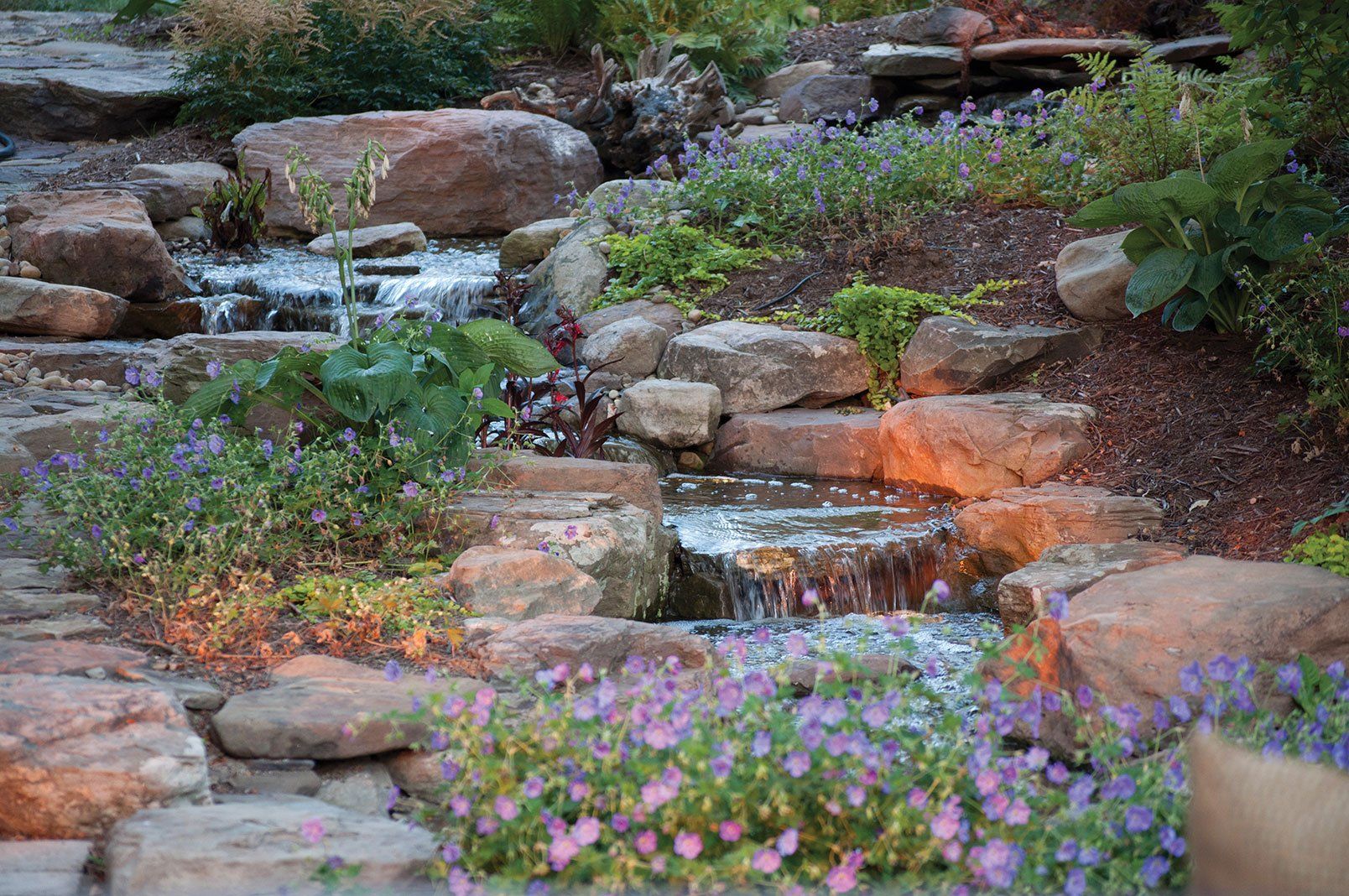 Multi level pondless backyard Ohio waterfall with large natural boulders and flowers