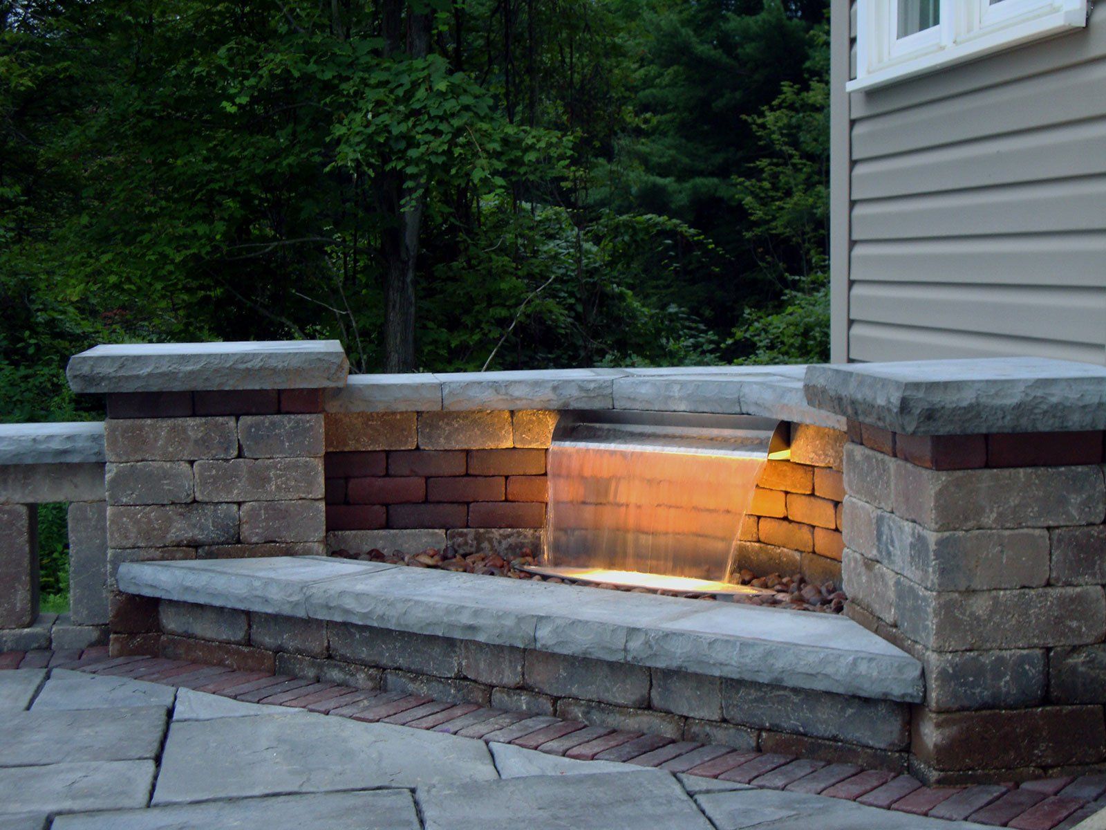 Unilock paver garden wall with water feature spillway and lighting