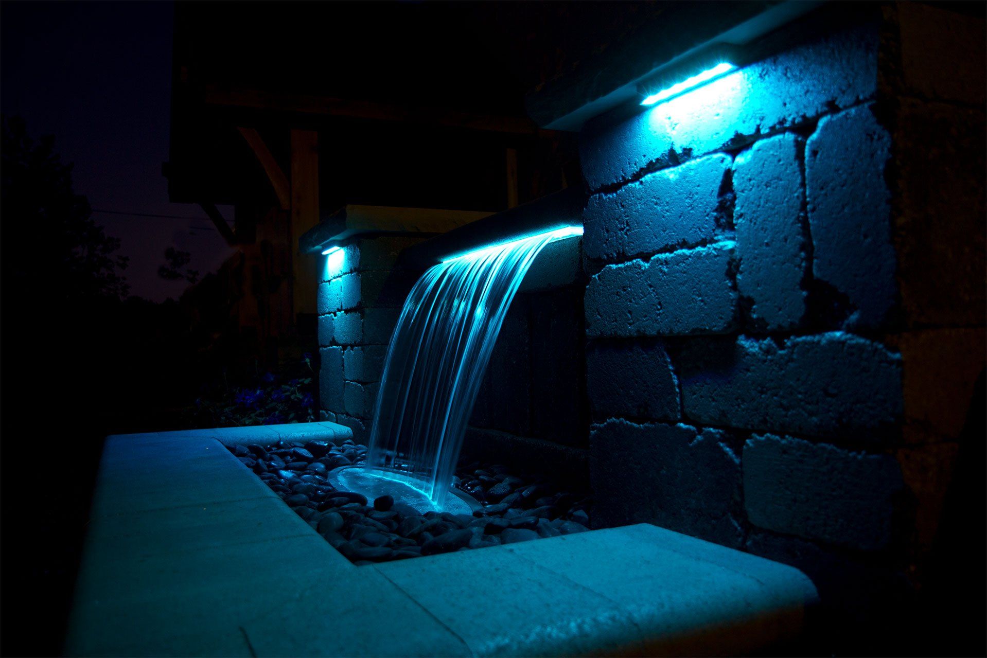 Ohio patio with a waterfall spillway and color changing lights at night
