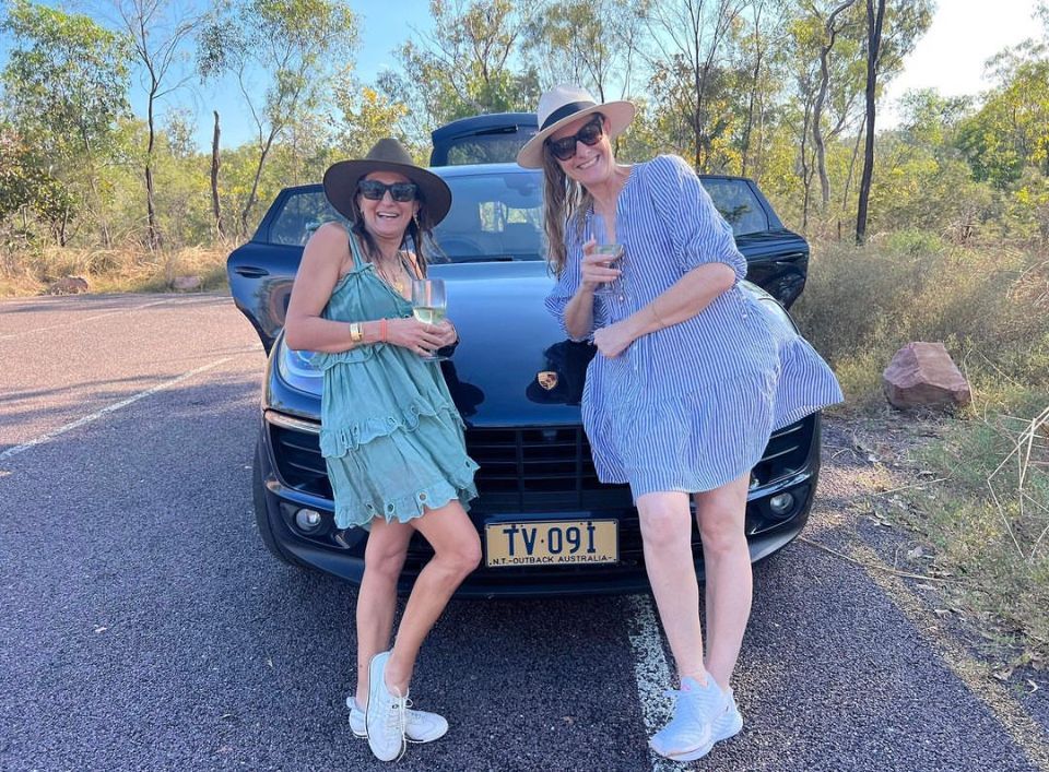 Two women standing next to a car with a license plate that says tv091