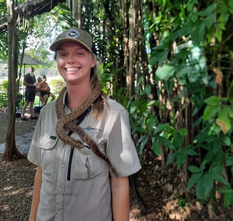 A smiling woman with a snake around her neck