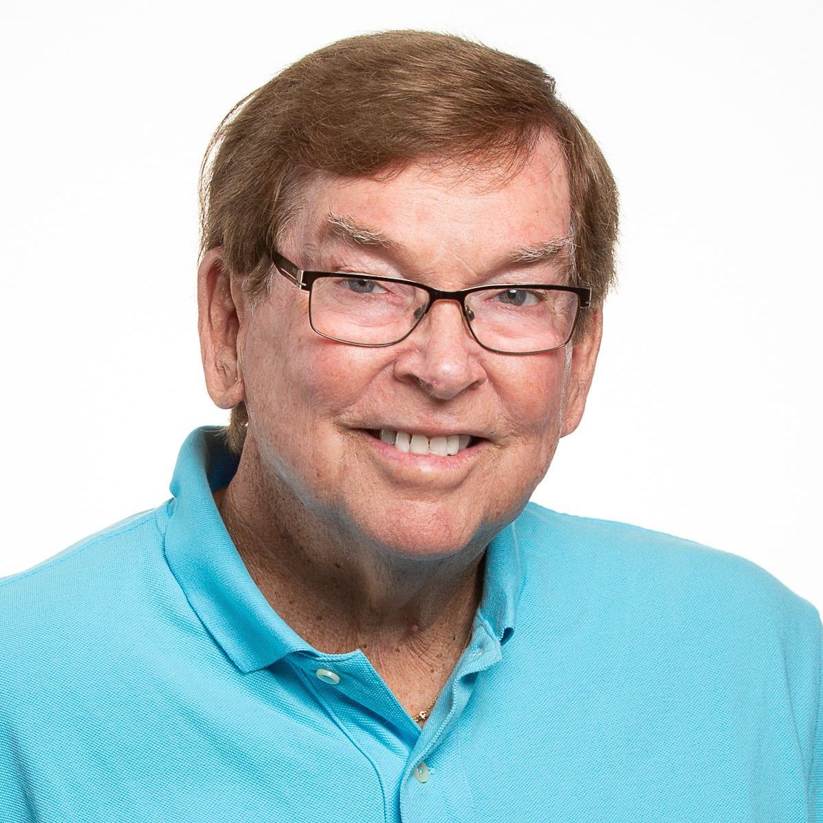 A man wearing glasses and a blue shirt is smiling for the camera.