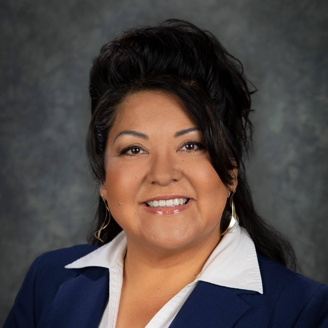 A woman in a blue jacket and white shirt is smiling for the camera.