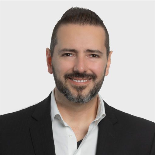 A man with a beard is wearing a black suit and white shirt.