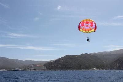 A person is parasailing over a body of water.