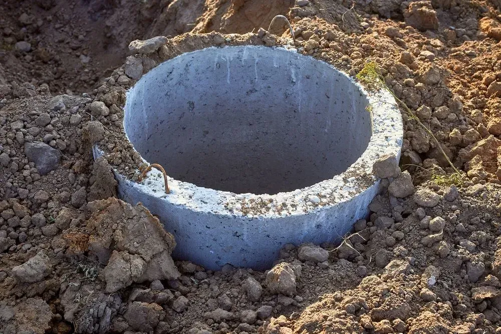 A concrete ring in a hole in the ground, likely a well or drainage installation.