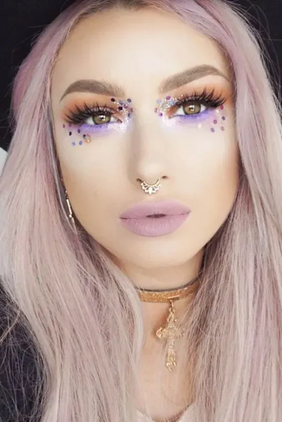A close up of a woman 's face with makeup and a nose ring.