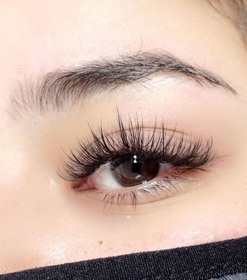 A close up of a woman's eye with long eyelash extensions.
