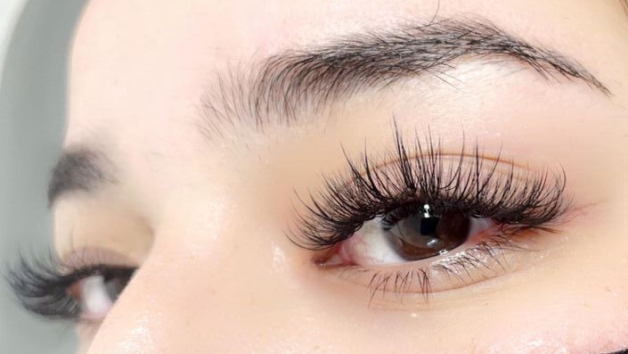 A close up of a woman 's eye with long eyelash extensions.