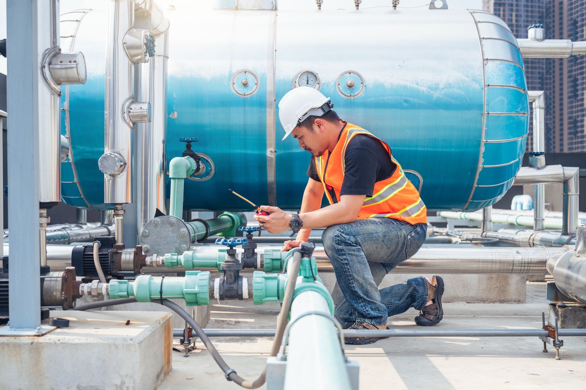 A man is working on a pipe in a factory.