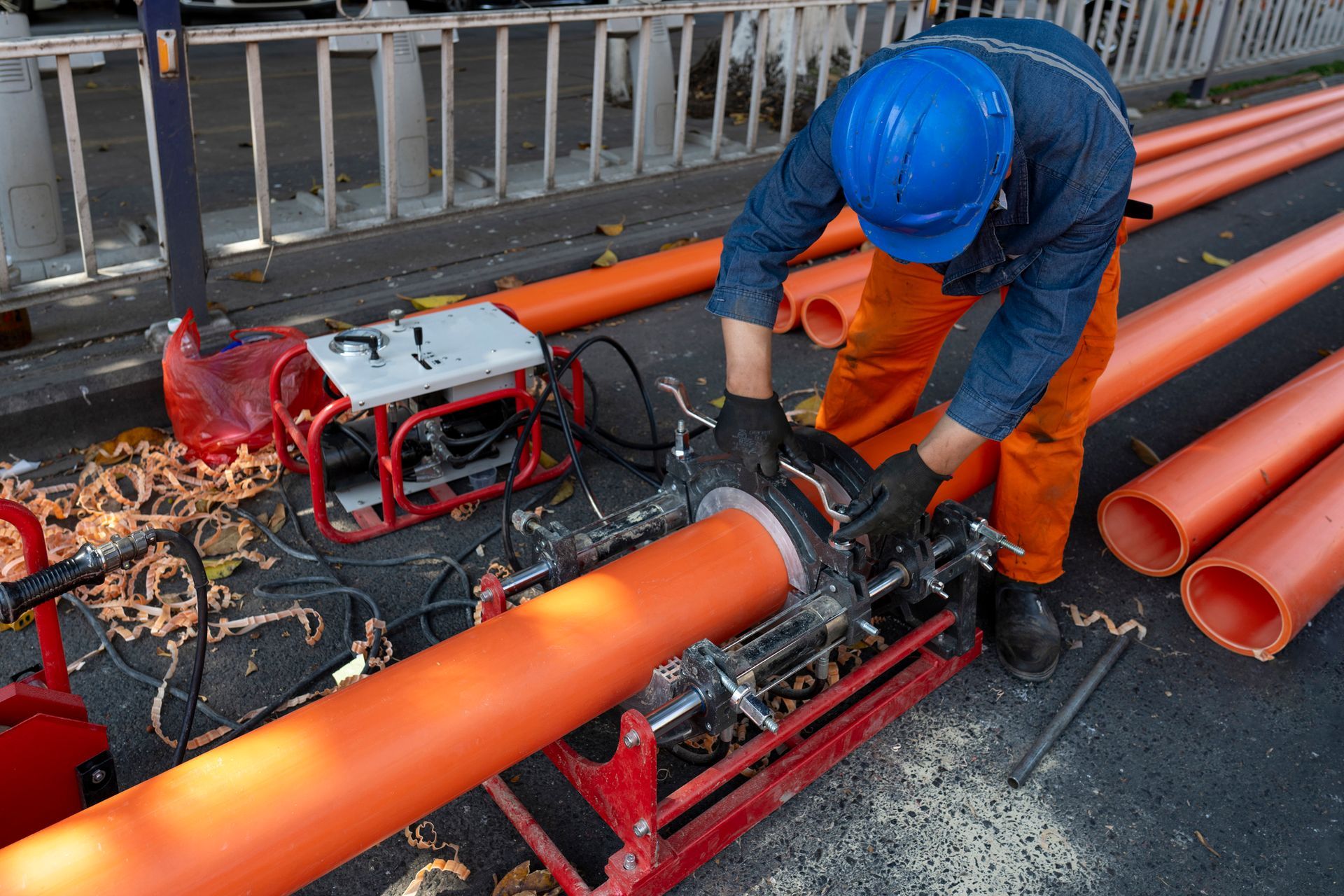A man wearing a blue hard hat is working on an orange pipe