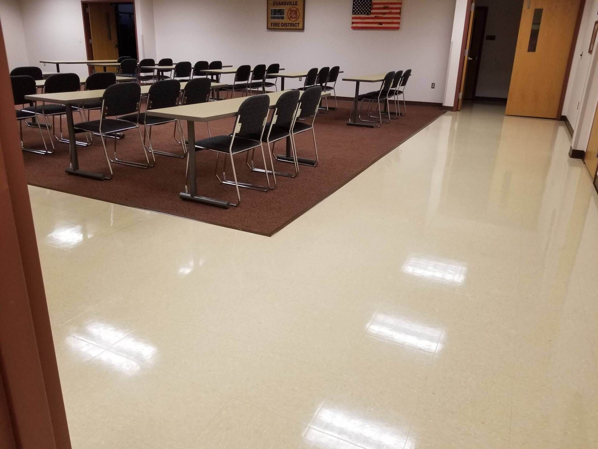 A room with tables and chairs and an american flag on the wall