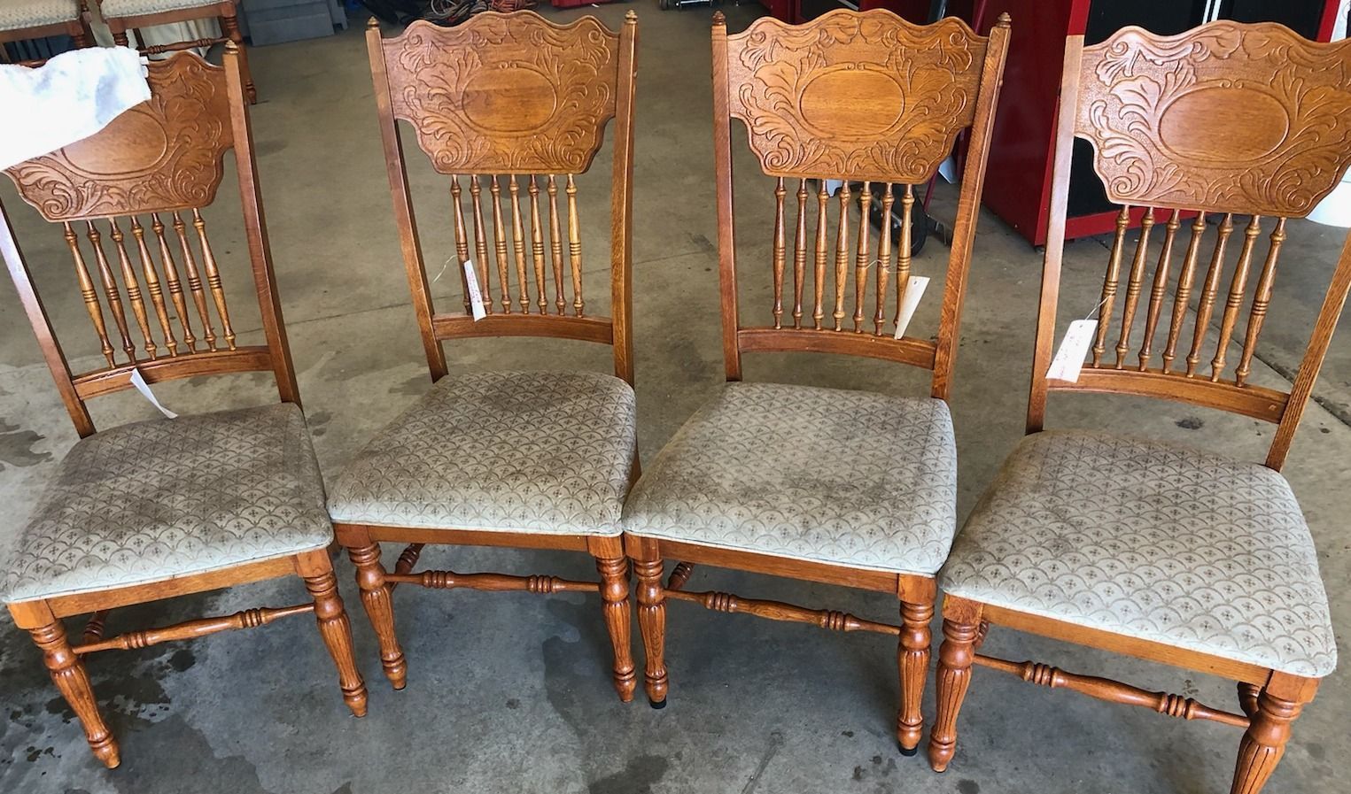 Four wooden chairs are lined up in a row on a concrete floor.