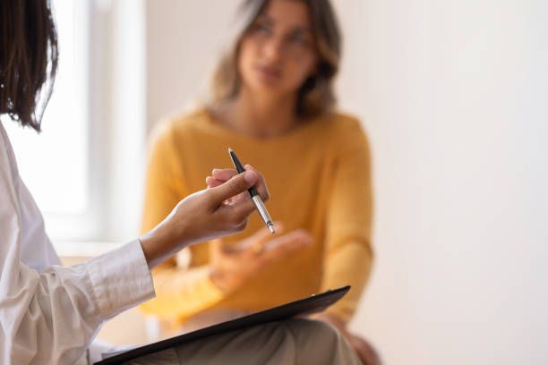 A woman is holding a pen while talking to another woman.