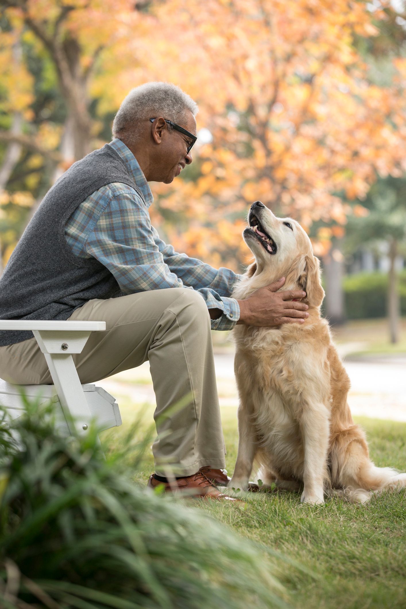 A man is sitting on a bench petting a dog.