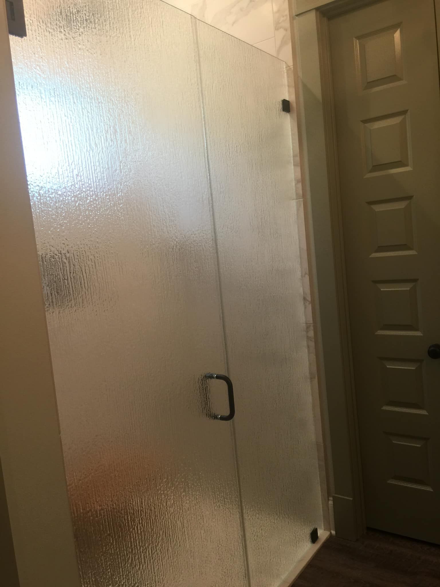 A bathroom with a glass shower door and a door.